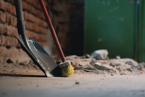 pala y escoba en el polvoriento fondo del piso del sitio de construcción.